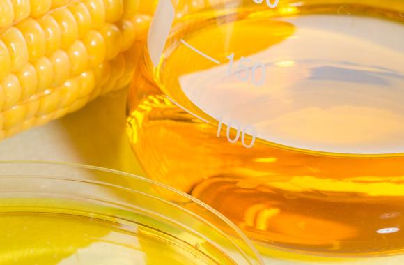 An image of corn next to a beaker filled with corn-based ethanol