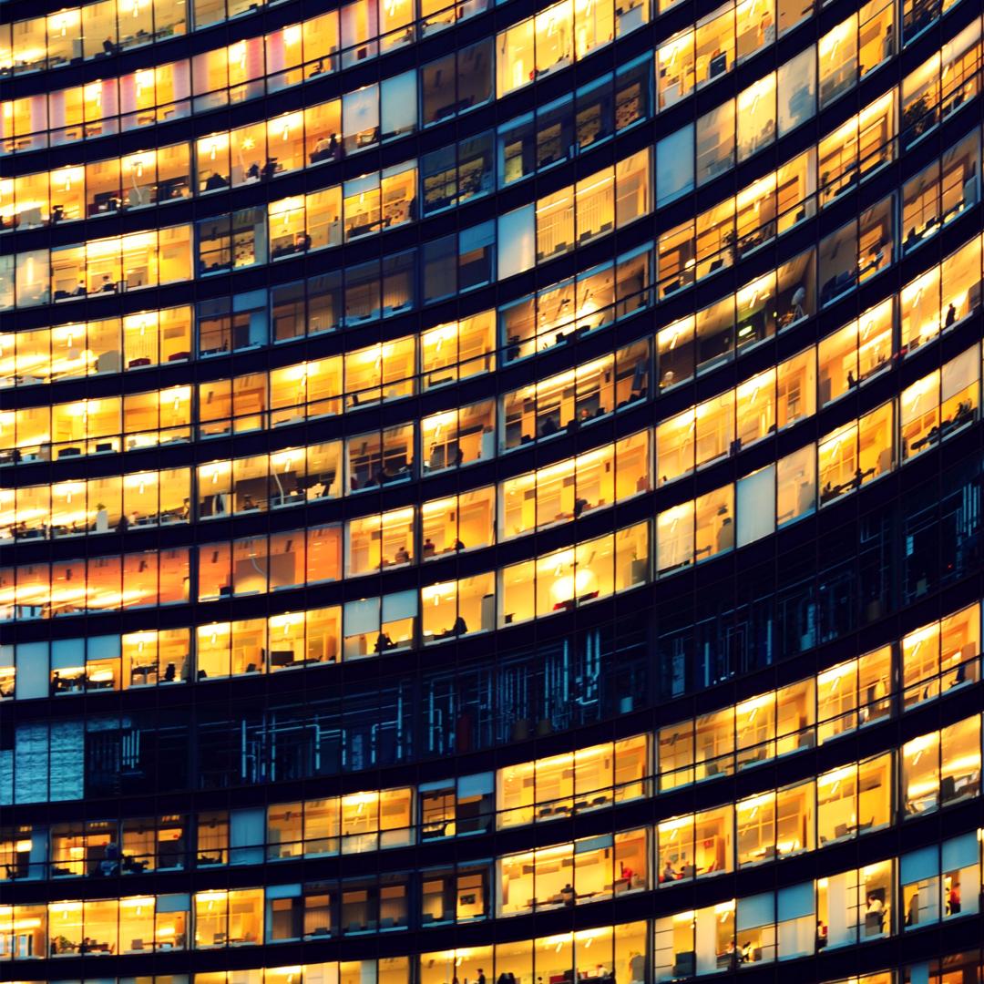 Office building exterior showing many floors of indoor lit offices
