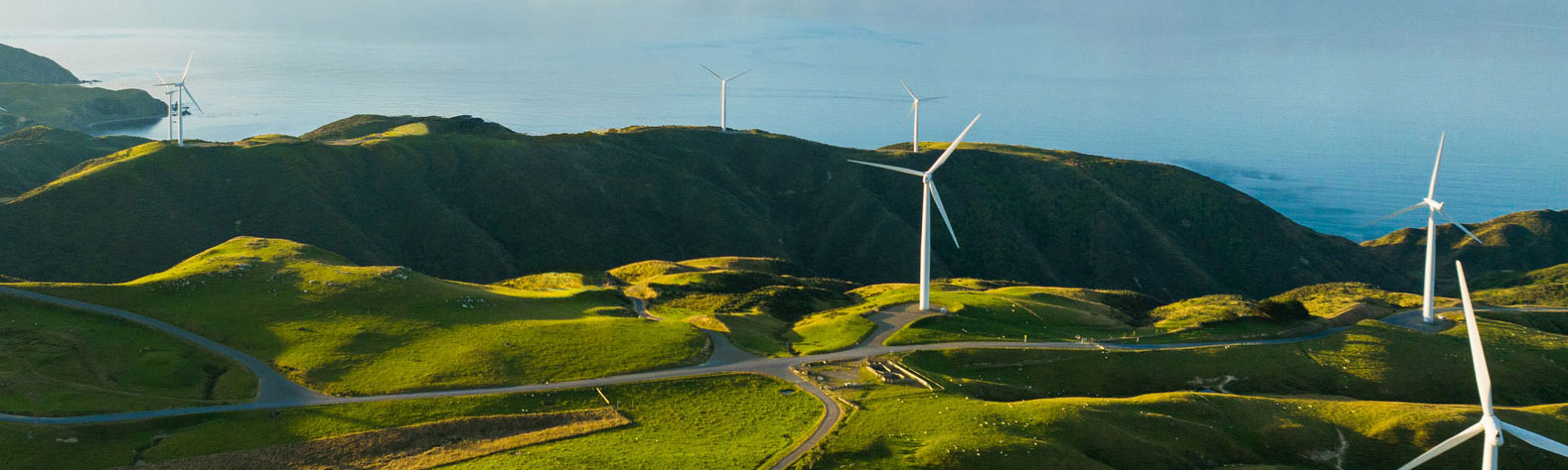 Rolling hills with wind turbines beside ocean